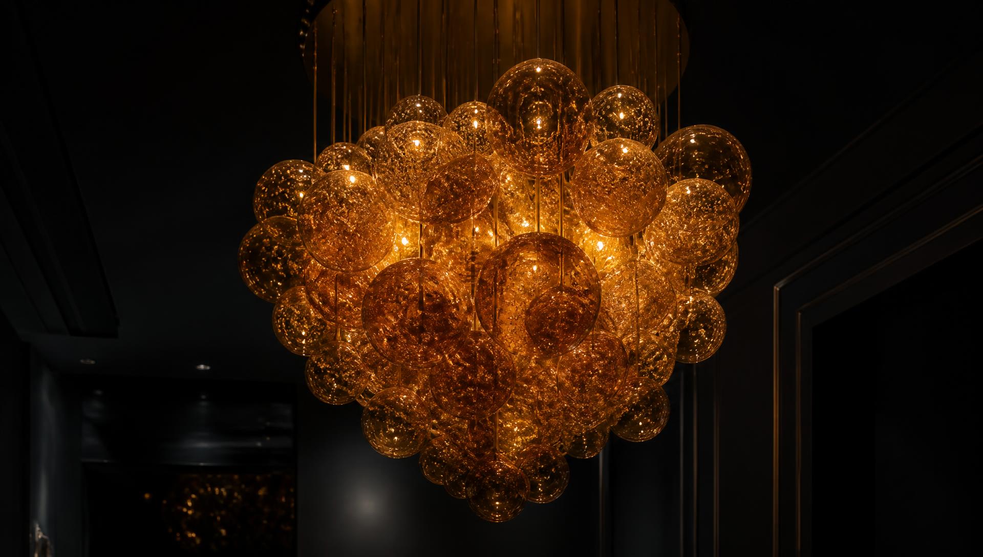 Clustered hand-blown amber glass chandelier glowing in a dark interior